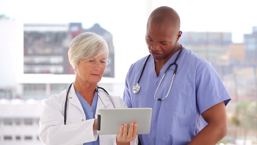 Happy doctor and nurse looking at a tablet pc in a bright room