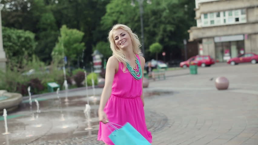 Happy woman with shopping bags in city, slow motion