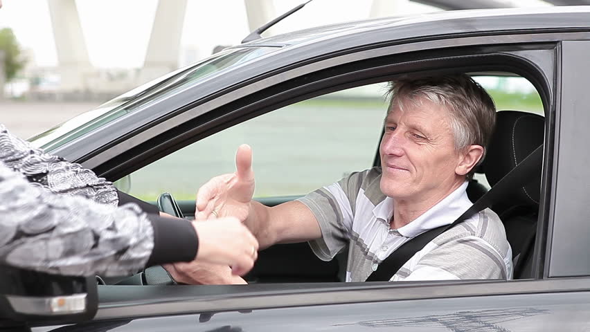 Mature Caucasian man get ignition key sitting in new car, starting and get a move on