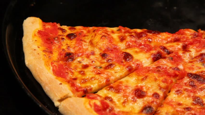nippers takes pizza slice from frying pan close up