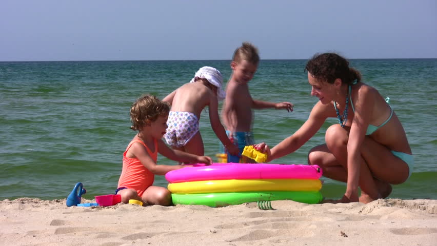 mother with children play on beach 