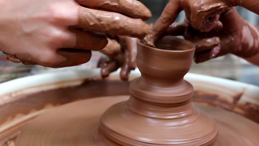 artwork on clay pottery with children pupil and teacher hands on wheel
