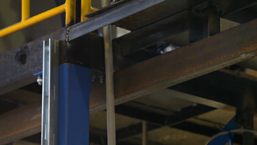 video shows metal construction installation process. This close-up shows metal cutting with small hand grinder with sparks flying down and metal is being cut. Video is taken indoors at factory site.