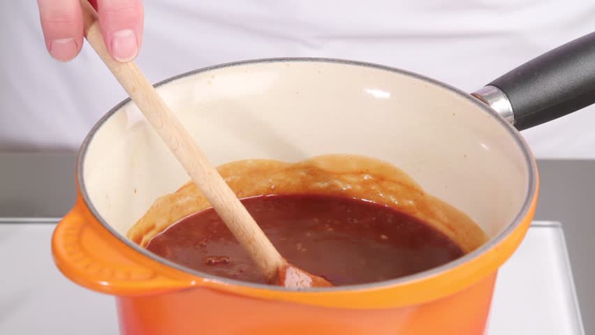 Barbecue sauce being spiced with chilli powder