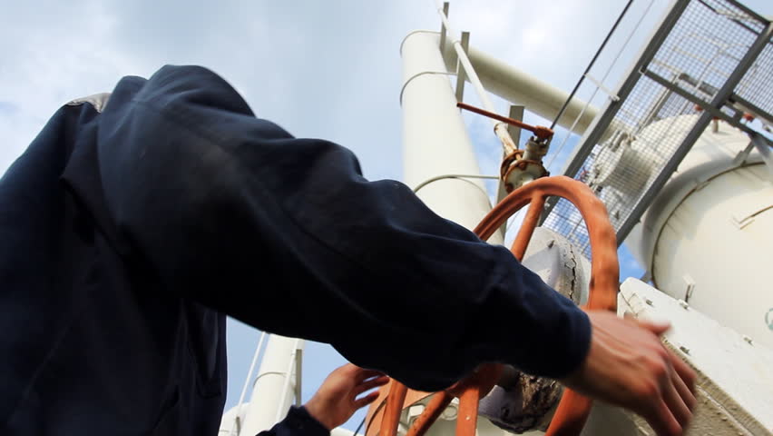 young engineer in orange helmet open valve on gas cleaning installation, close-up from below