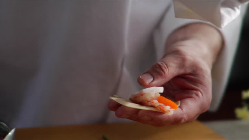 Chef prepares Asian shrimp appetizer and camera pan over as he places it on a serving plate.