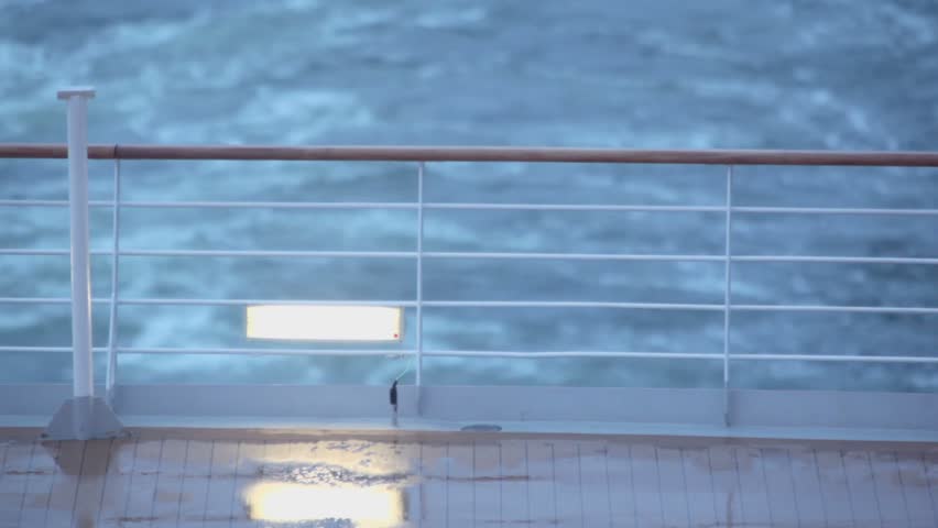 Froth trail after ship which floats in sea with fence and light on deck