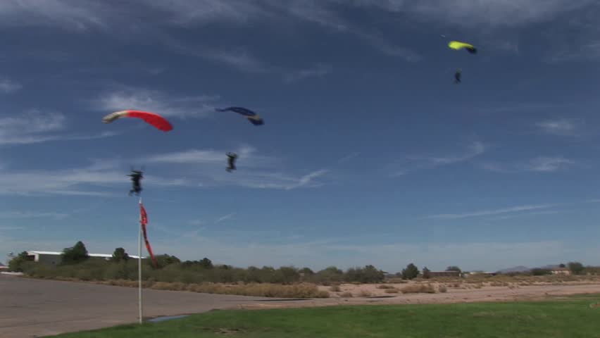 Three Skydivers Landing In A Field