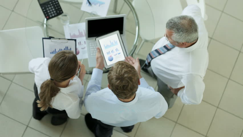 Business team of three comparing digital data and its hard copy during discussion