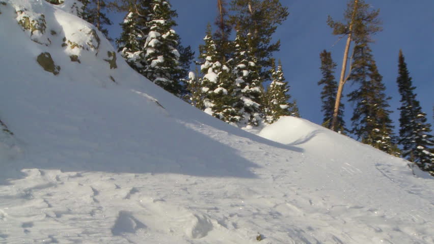 SLOW MOTION - Male skier dropping in to steep black-country terrain