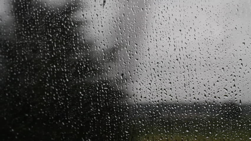 Abstract shot of rain water running down a moving car's window