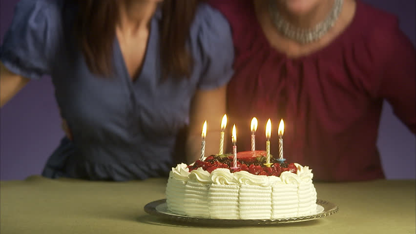 Mother and grown up daughter by a birthday cake