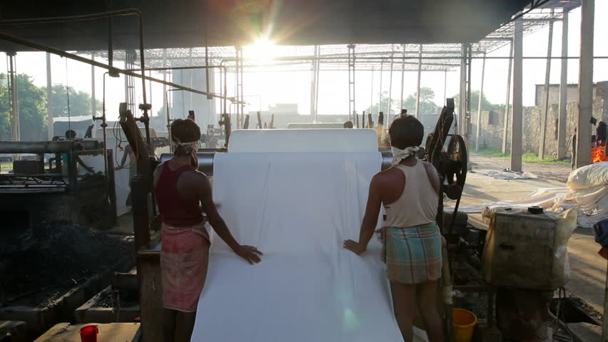Rajasthan, India - CIRCA May 2011: Newly dyed fabric being washed and rolled, Sari garment factory