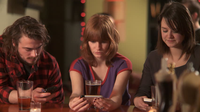MS, PAN, Selective Focus, Three friends sitting at a bar using their mobile phones