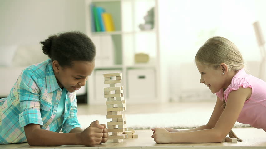 Lovely girls playing a game of risk trying to move wooden blocks without destroying the whole tower