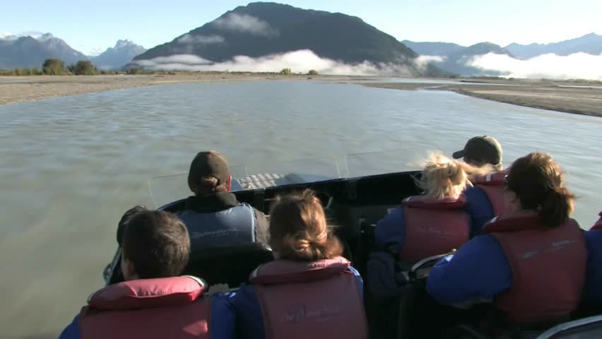 QUEENSTOWN, NEW ZEALAND - CIRCA JULY 2011: Jet boat with tourists travelling at fast speed down the braided Dart River circa July 2011 in Queenstown, New Zealand.