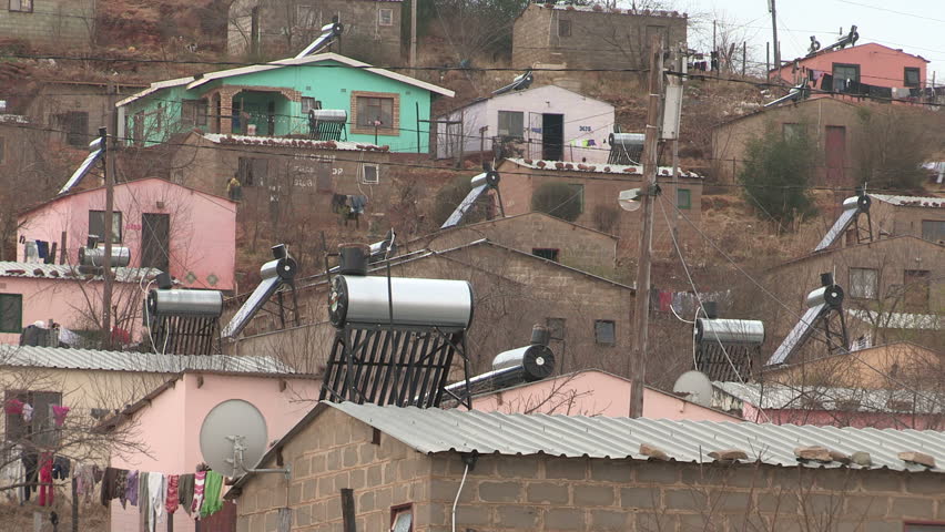 A wide shot of African community  that uses solar power. You see solar panels on roofs to warm up there geysers . 