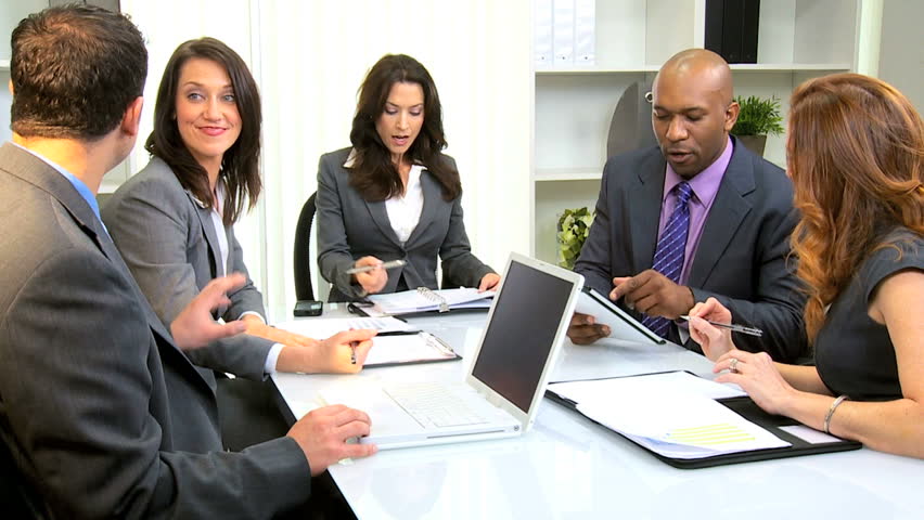 Multi ethnic business team using modern wireless technology in city boardroom
