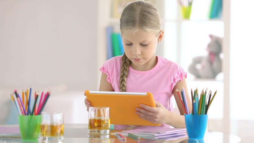 Lovely schoolgirl learning how to use a digital tablet
