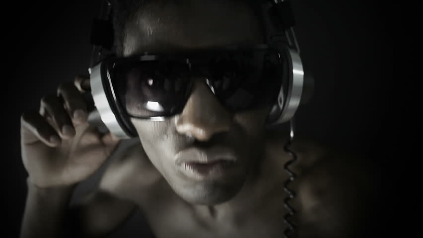 young cool african guy waving and dancing with headphones and glasses on a black background