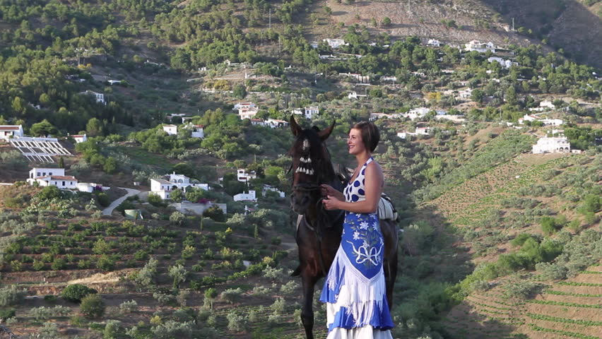 Woman standing on a hill in Andalusia with her horse
