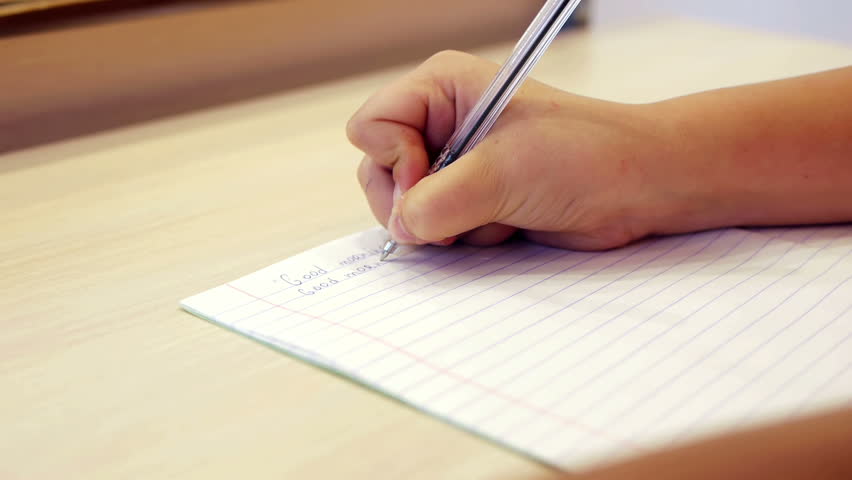 Close-up of schoolgirl hand writing task on the copybook