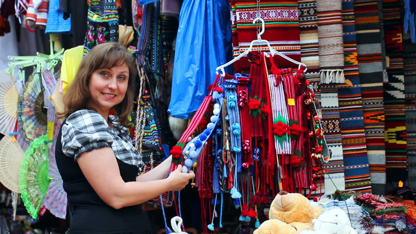 pretty woman chooses Ukrainian folk ornaments on souvenir market