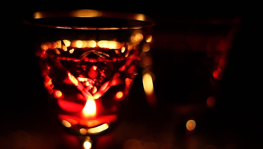 Reflections of candle on two glasses of vine.
