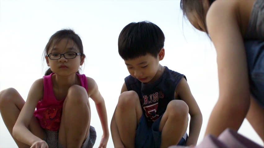 Siblings playing on the beach trying to form Sand Castle.