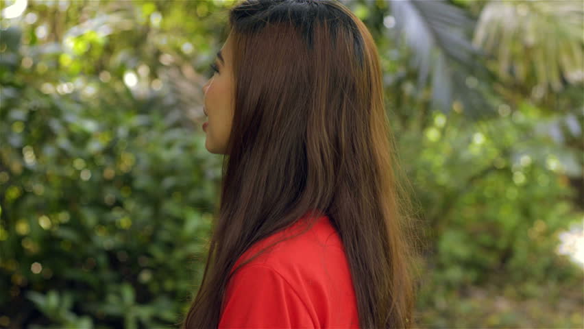 Young Asian woman turning to face the camera, smiling and putting both thumbs up, then continuing to smile some more.
