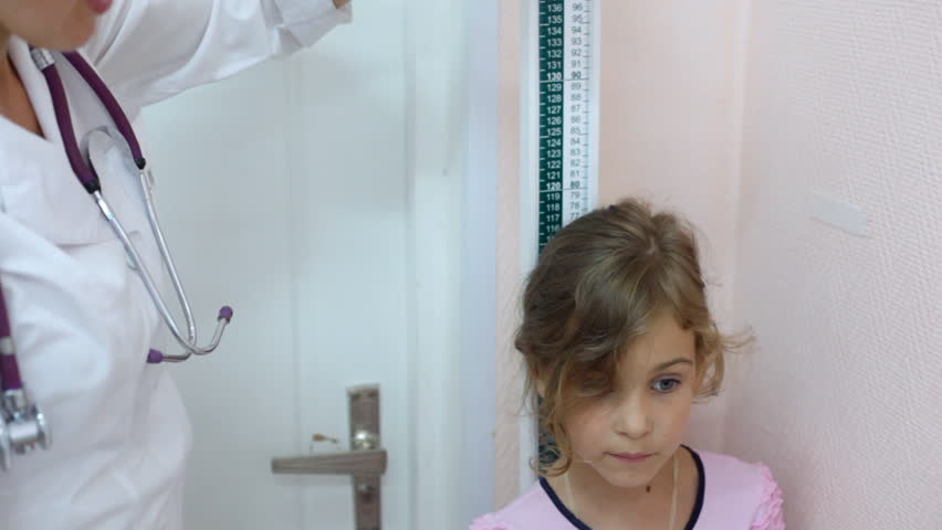 woman doctor measures growth of little girl by ruler