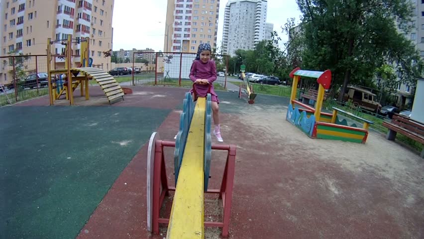 Little girl goes for a drive on teeterboard in house yard