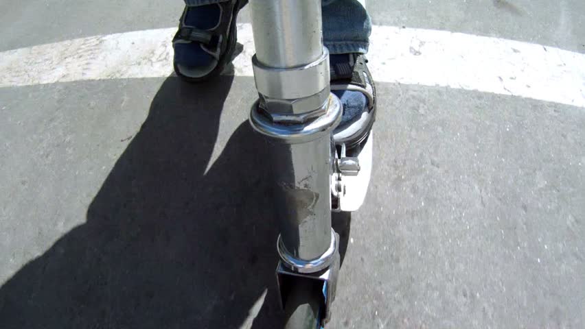 Teenager goes for a drive on the scooter, push away by foot from asphalt