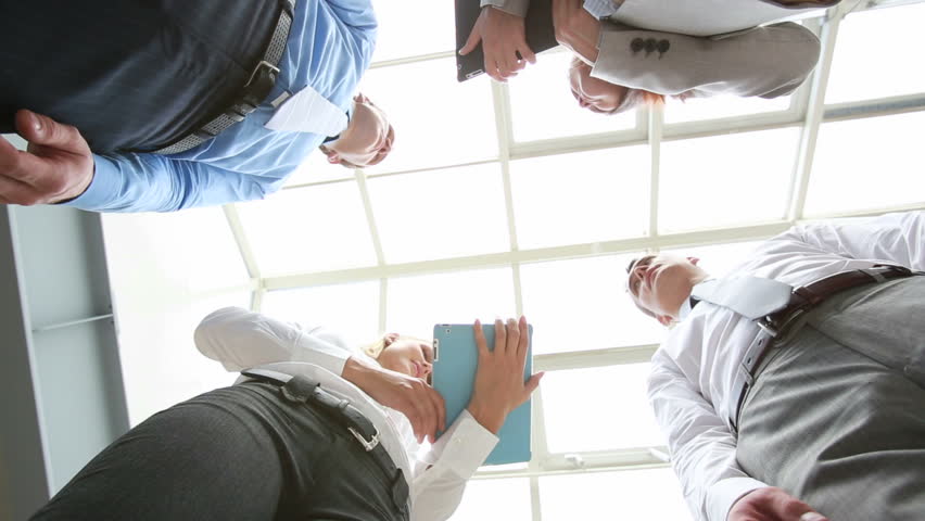 The below view of satisfied businessmen shaking hands, their female colleagues smiling to each other