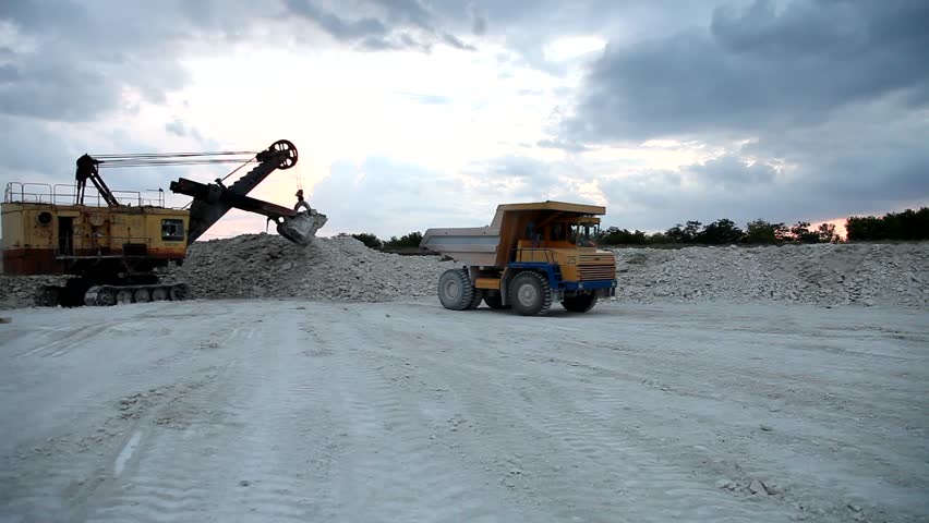 Heavy mining dump truck being loaded with iron ore