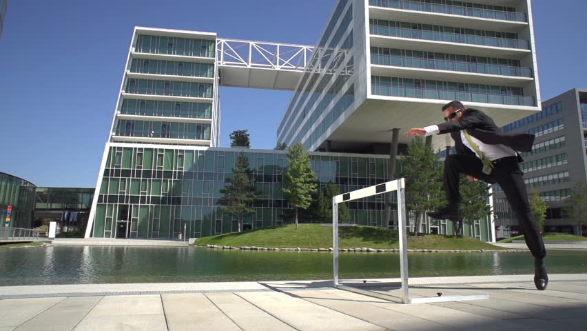 dynamic hurdler in business suit running over hurdle in slow motion