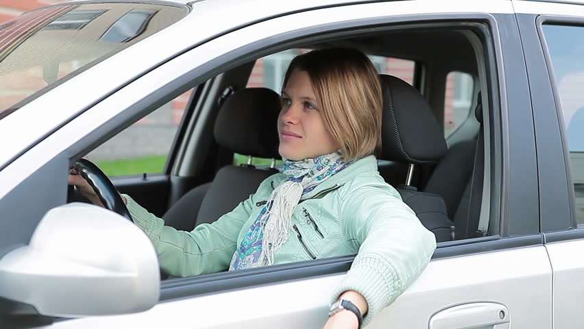 Happy pretty Caucasian woman looking at camera and waving hand in window