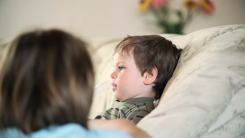 Sick little boy and mother using nebulizer to inhale the medicine