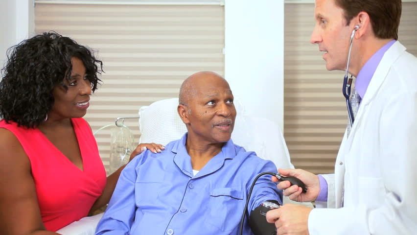 Hospital doctor taking blood pressure of senior male African American patient