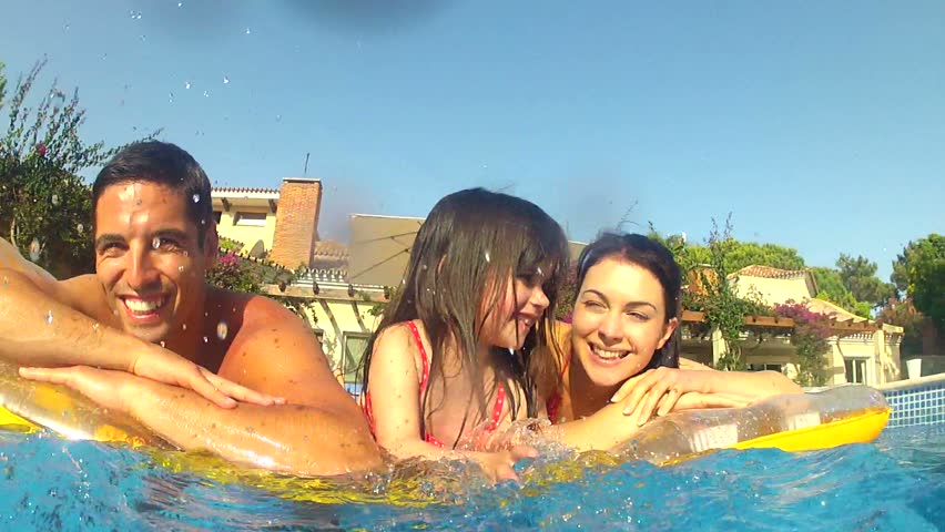 Family lying on inflatable airbed in splashing camera position.