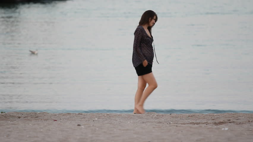 Young pretty woman walking alone on the beach