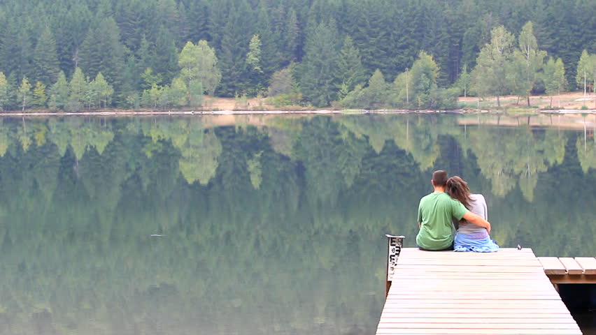 Couple relaxing on a pontoon and admiring the scenery of a mountain lake