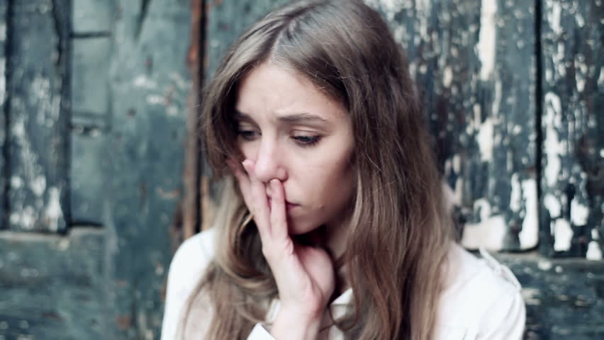 Sad, depressed young woman standing by the old doors, stabilized shot
