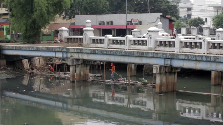 Indonesian man working in an open sewer of Jakarta