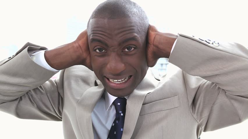 Black businessman shouting the hands on his ears with a bright window in background