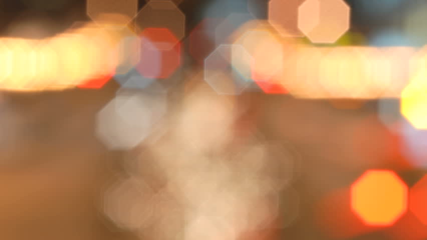 Time-lapse of a de-focused downtown traffic light with cars passing by. 