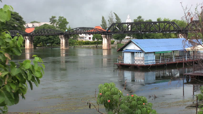 A long-tail boat speeds under the famous Bridge on the River Kwai near Kanchanaburi in Western Thailand.