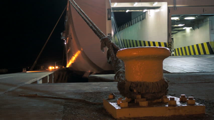 A close up shot of a large ferry being loaded during the night while moored at the dock.