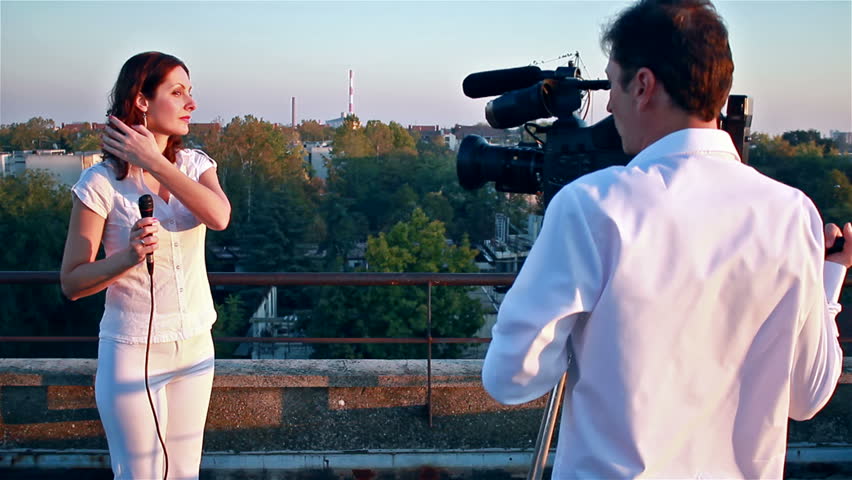 TV crew on the set ; TV crew prepares to shooting a weather report at the top of the building
