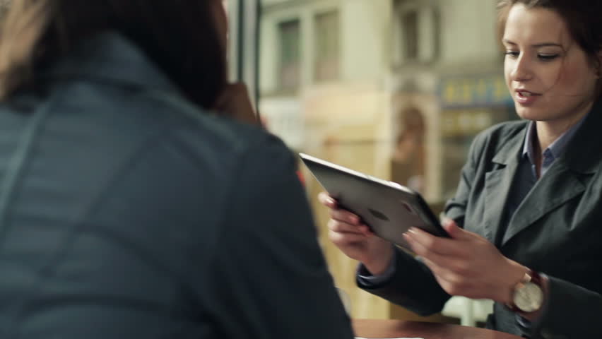 Young business people with tablet computer in cafe, steadicam shot
